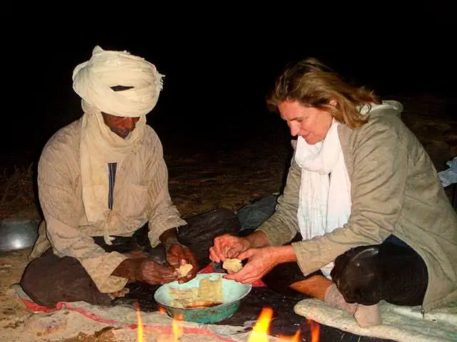 Tuareg woman preparing Taguella bread in the Sahara.