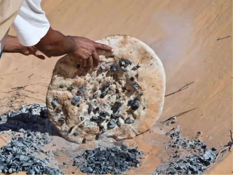 Sand-baked Taguella bread resting on desert sands.